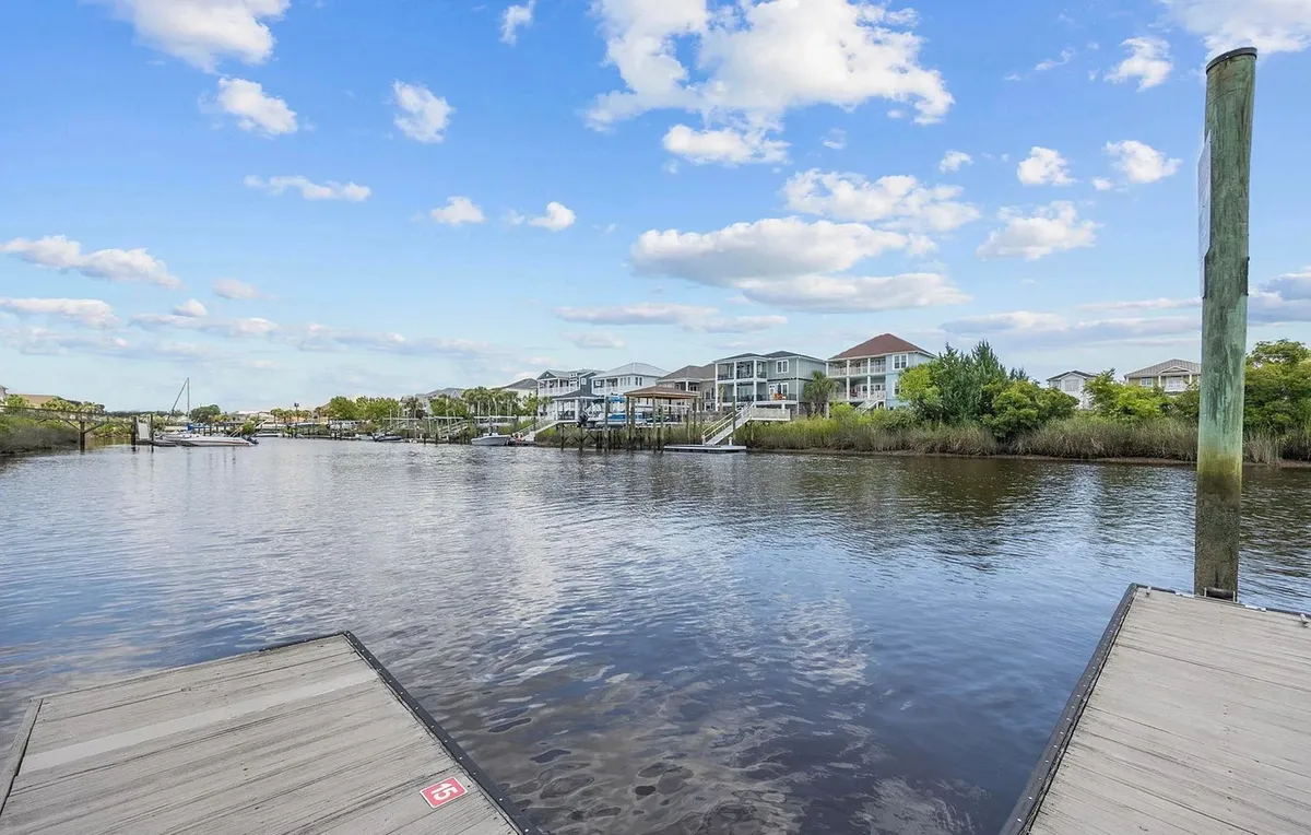 A peaceful waterfront scene featuring calm waters, several docks, lush greenery, and waterfront homes. The environment exudes relaxation, with the opportunity to enjoy fishing, boating, and nature walks right outside your door.