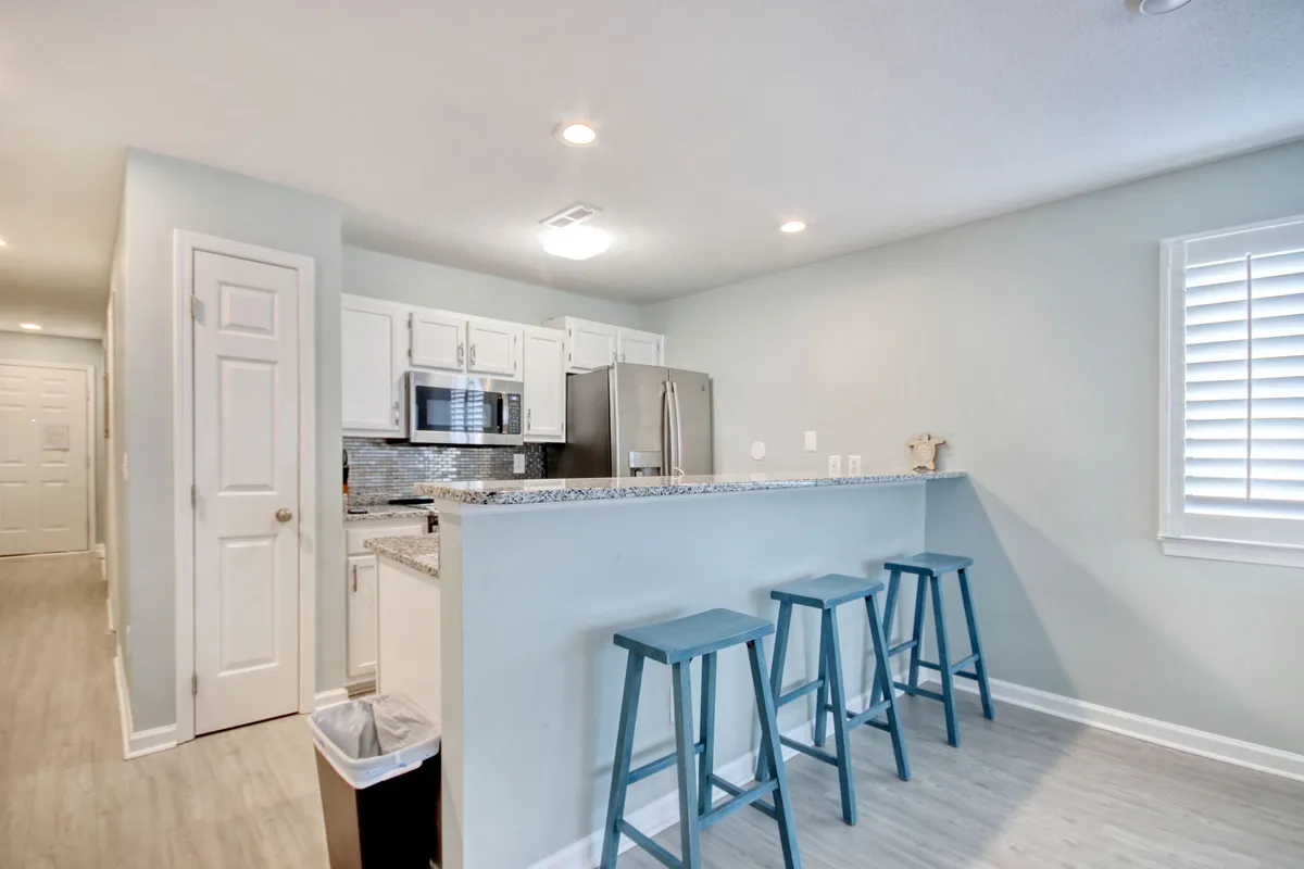 A modern kitchen and dining space with sleek granite countertops, bar stools, and stainless steel appliances. The space is bright and open, ideal for casual dining, morning breakfasts, and social gatherings.