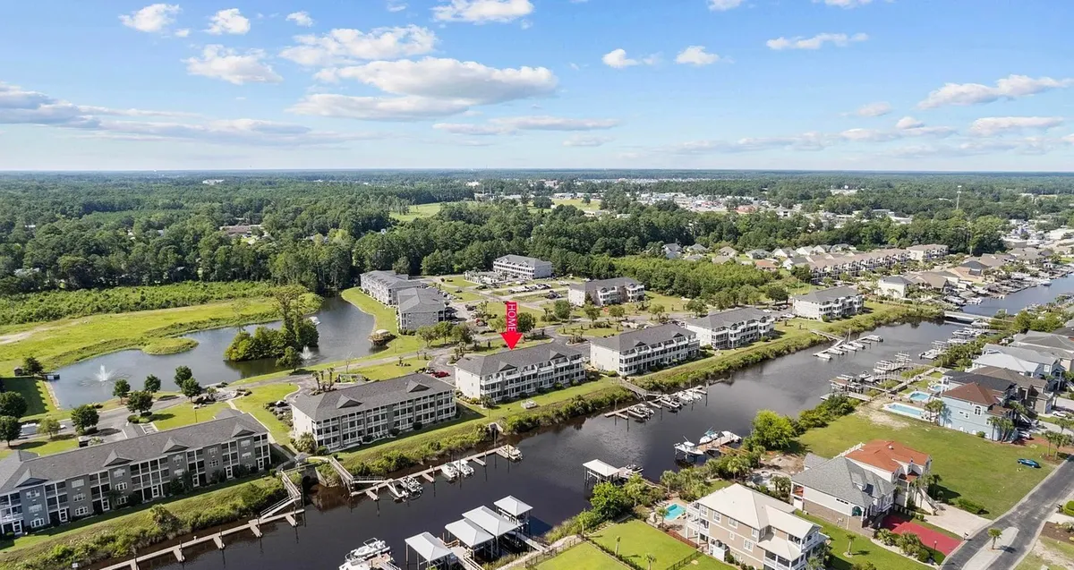A scenic view of community waterways, marinas, and lush greenery, with residential buildings in the background. The area appears welcoming for leisurely walks, boating, and family gatherings by the water.